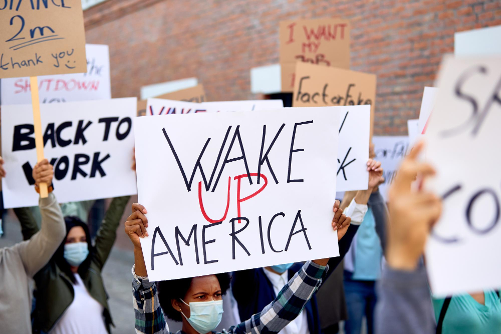 "Protesters holding signs, including 'WAKE UP AMERICA', calling attention to the biggest violations of constitutional rights Americans should be aware of."